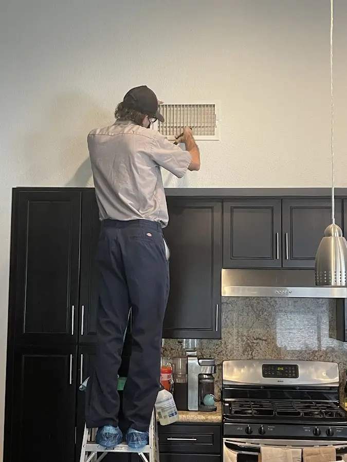Technician inspecting an air vent during HVAC service in Maysville
